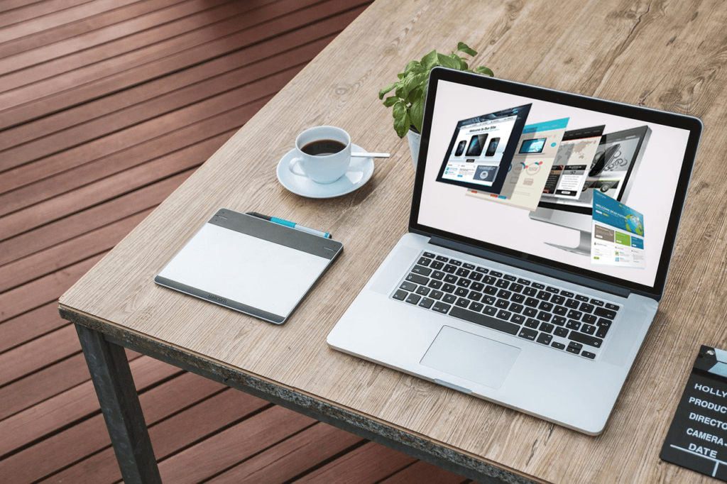 A desk with a laptop, graphics tablet and coffee cup, ready to start designing a website